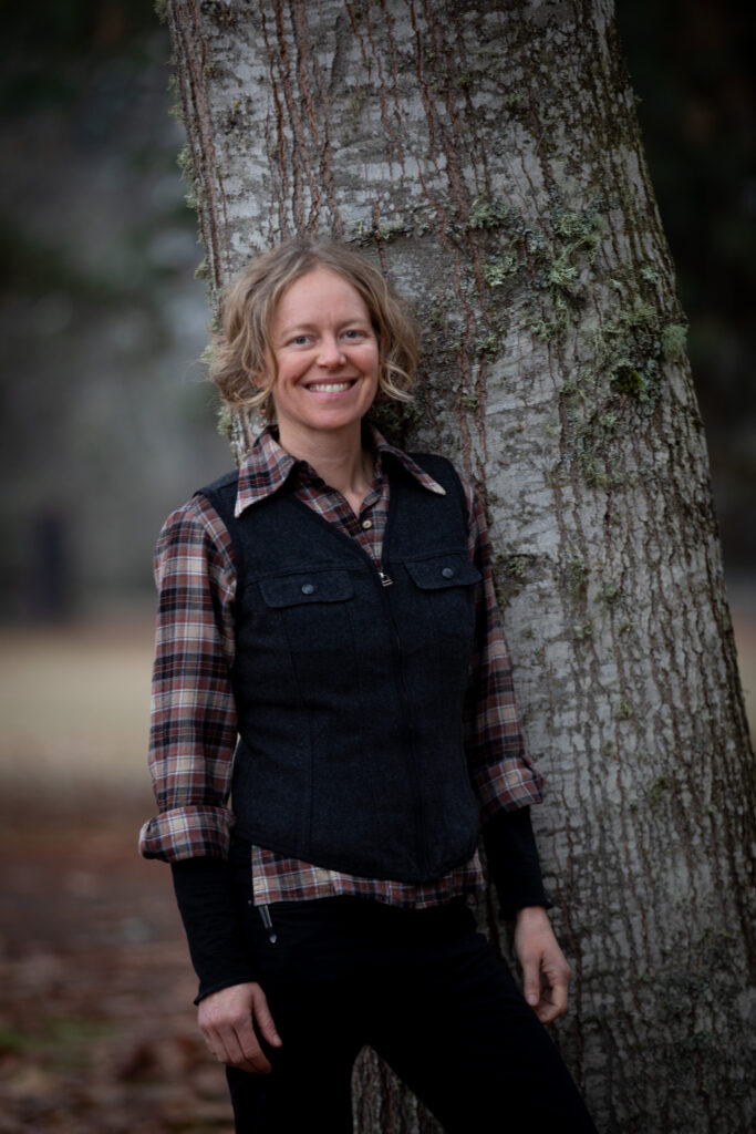 Georgia smiling standing next to a tree