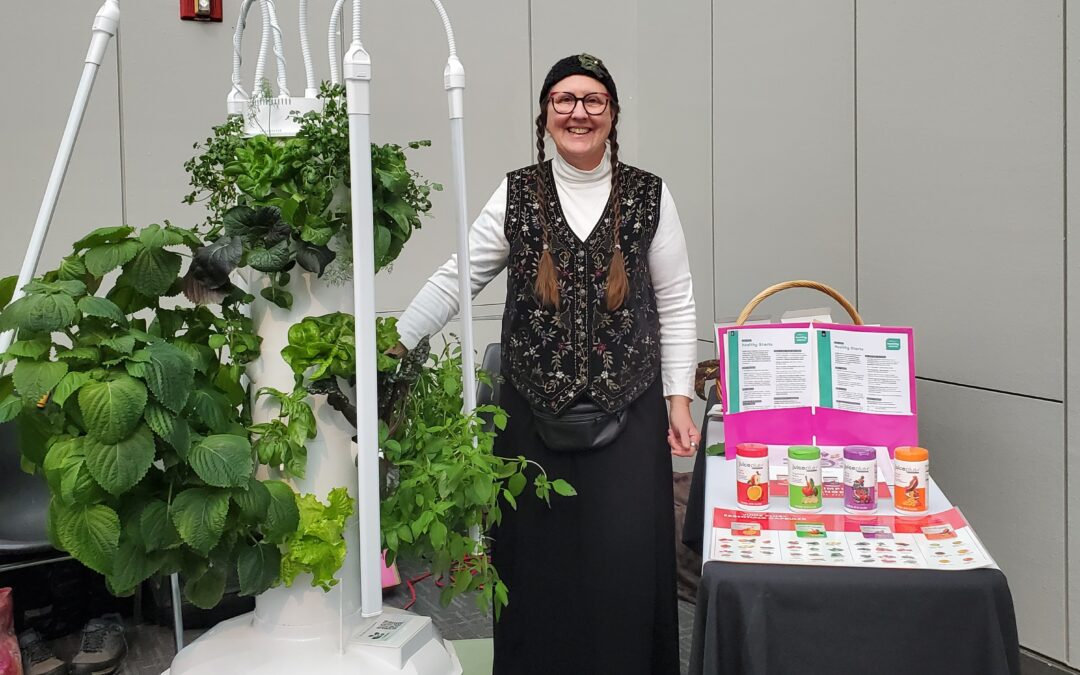 Linda standing by a tower garden and juice plus table